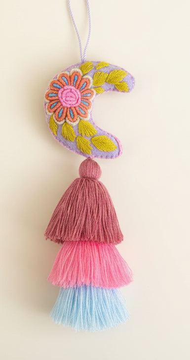 Decorative crescent moon with floral patterns and tassels on a dark background